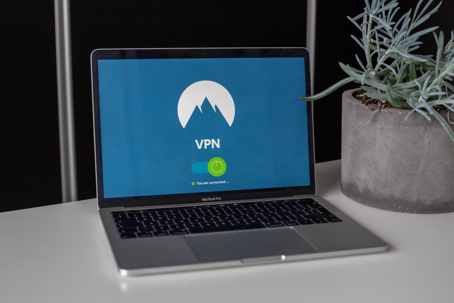 Laptop con pantalla de VPN y una planta suculenta en un escritorio, enfatizando la privacidad y seguridad en línea.