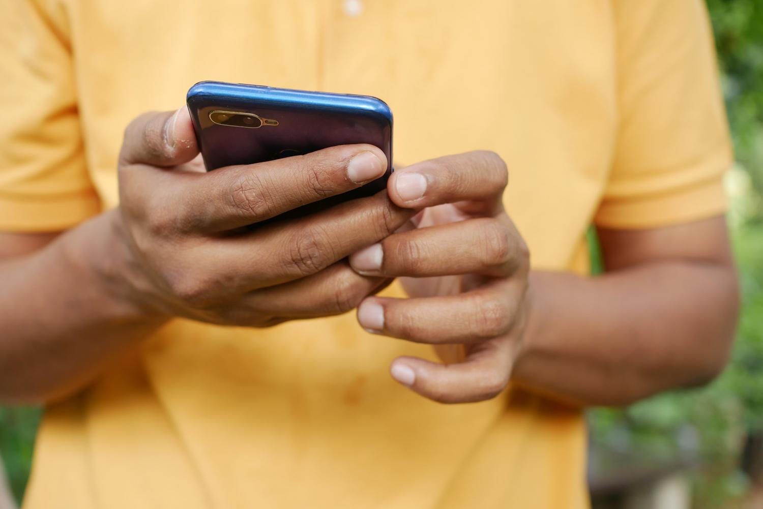 Persona utilizando un smartphone moderno en un entorno exterior, representando la conectividad 5G en el día a día.