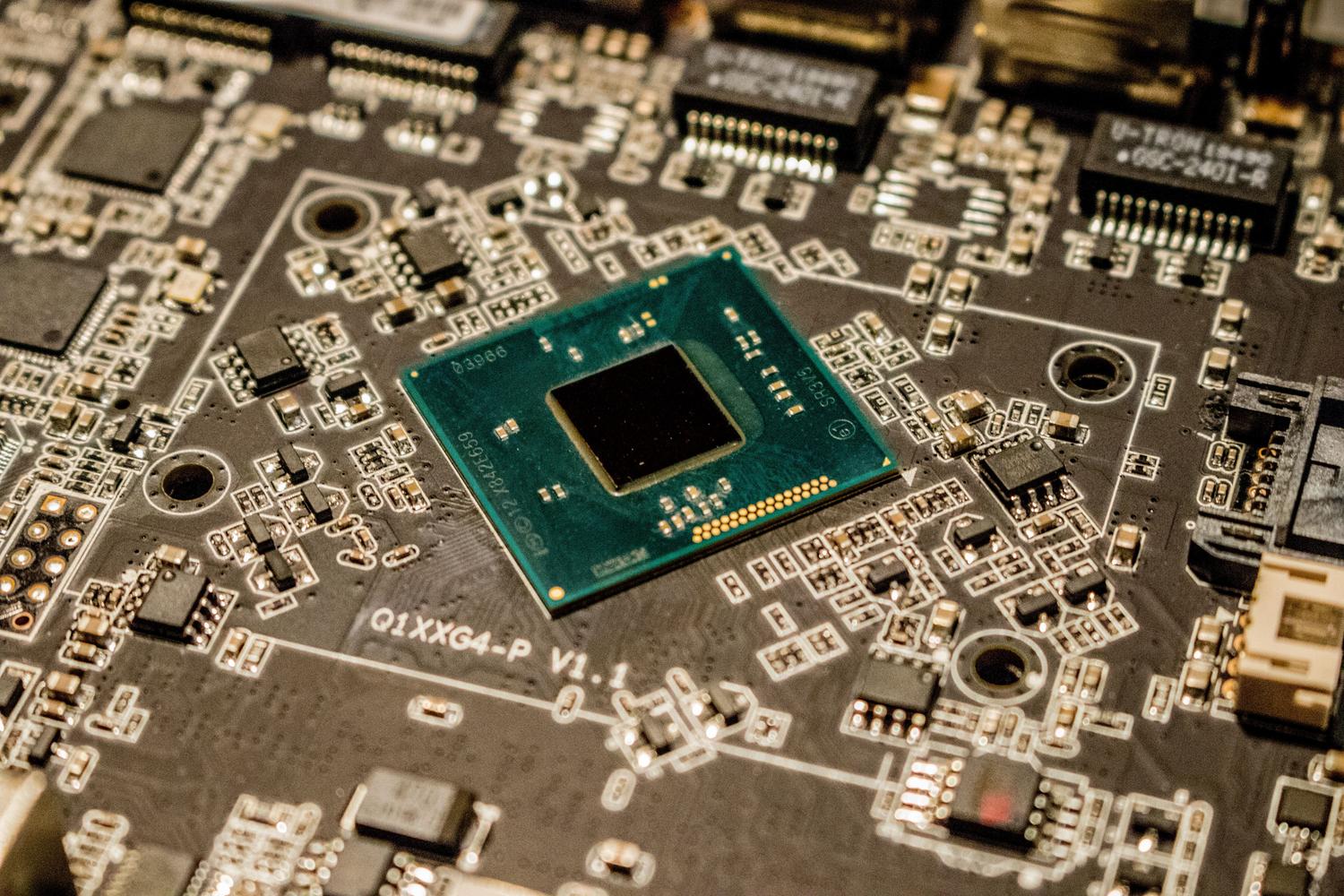 Primer plano detallado de un microchip en una placa de circuito impreso, ejemplificando el concepto de firmware como el cerebro básico del hardware.