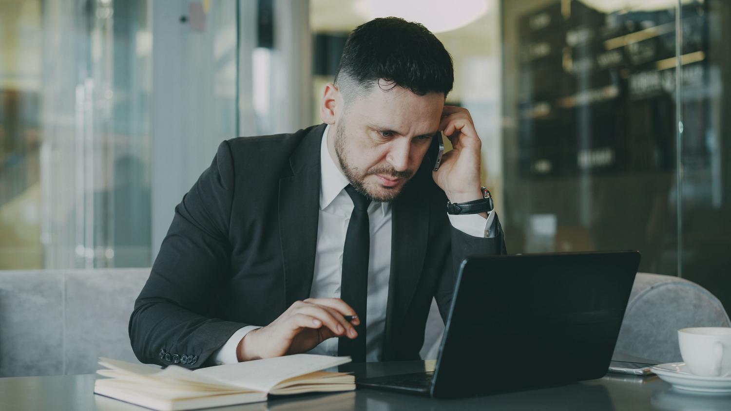 Profesional en oficina utilizando simultáneamente ordenador y teléfono, representando la productividad de una plataforma de comunicaciones unificadas.