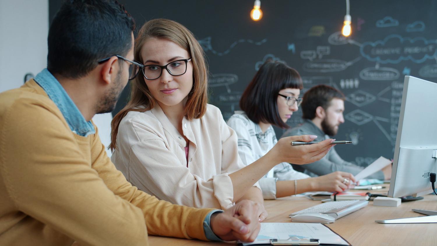 Grupo de jóvenes profesionales colaborando en un espacio de trabajo creativo, reflejando la comunicación interna fluida.
