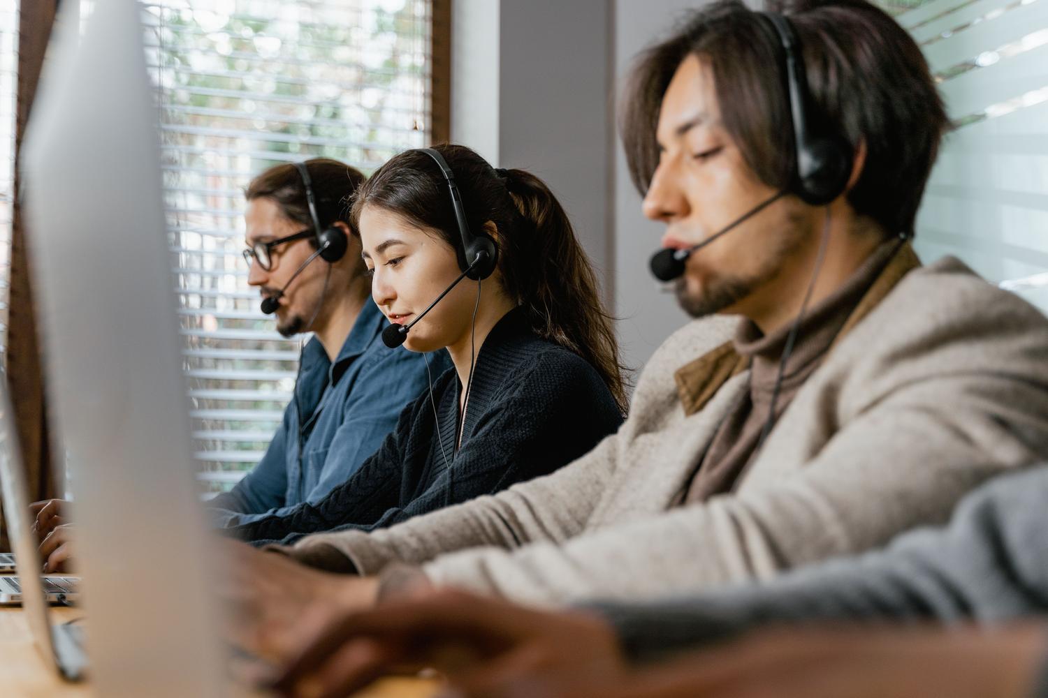 Equipo de agentes de centro de contacto trabajando coordinadamente con auriculares en un entorno de oficina moderno.