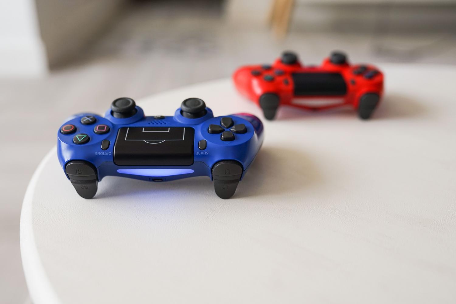 Primer plano de mandos DualShock 4 de PlayStation sobre una mesa blanca, ideal para ilustrar la calibración de sticks.