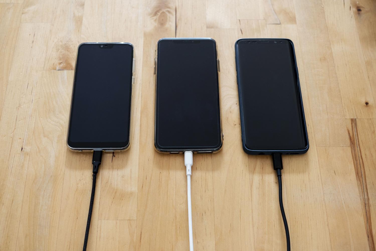 Varios smartphones cargándose simultáneamente sobre una superficie de madera, perfecto para consejos sobre optimización de batería y carga en MIUI.