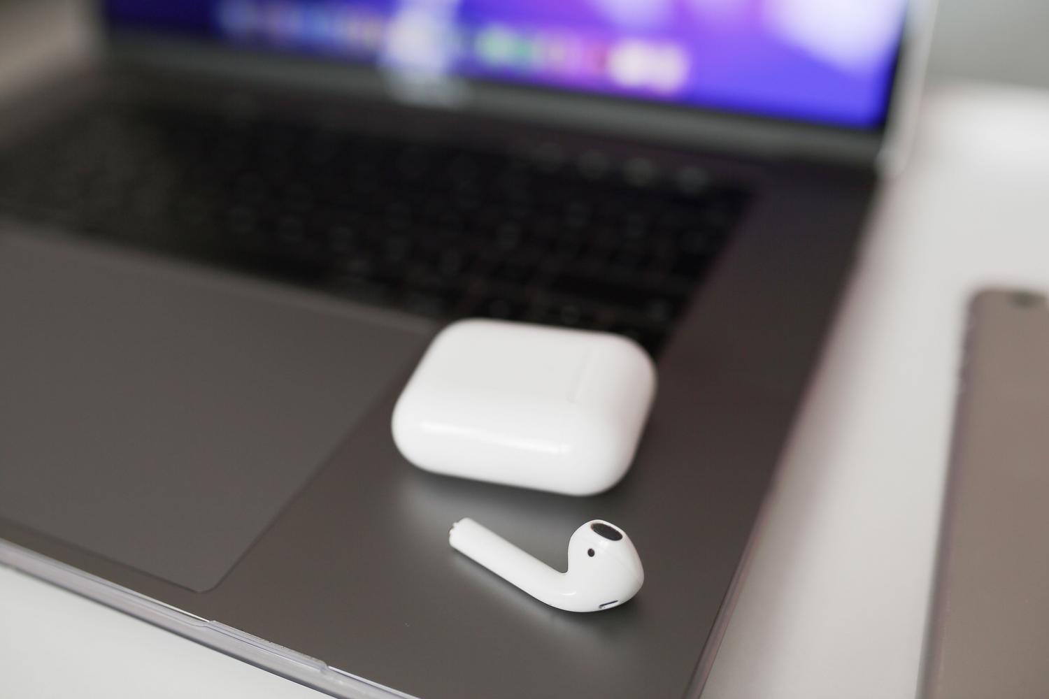 Auriculares inalámbricos blancos junto a un ordenador portátil Macbook