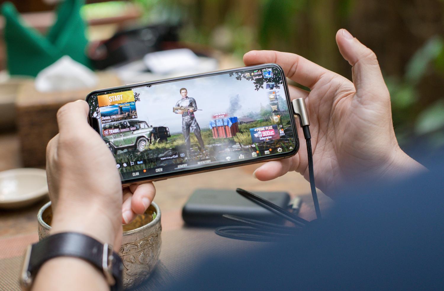 Persona utilizando un smartphone para jugar, ilustrando los simuladores de juegos de PS5 para dispositivos móviles.
