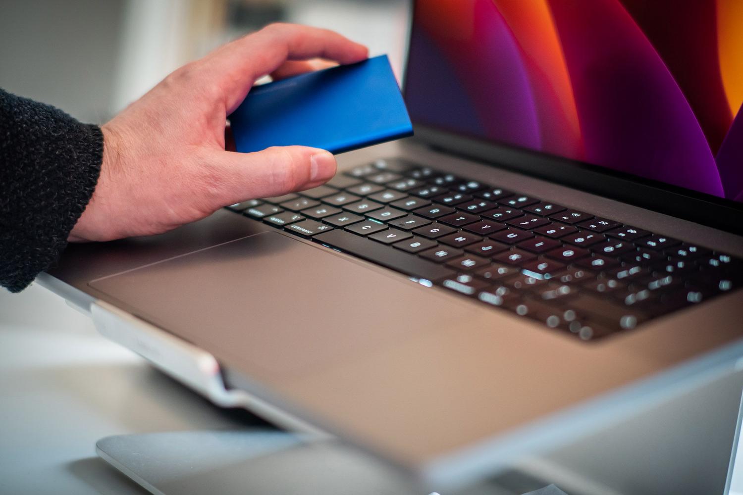 Mano conectando um disco duro externo a um portátil, representando o processo de backup manual.