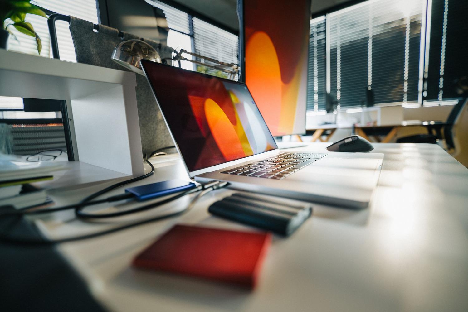 Espaço de trabalho moderno com portátil e discos externos, ilustrando a regra de backup 3-2-1.