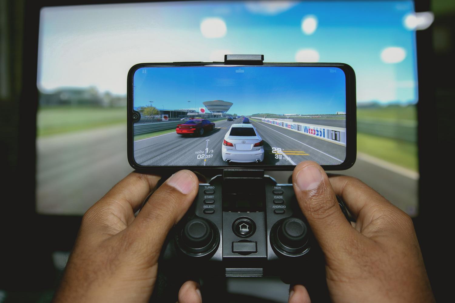 Primer plano de manos utilizando un mando de juegos conectado a un smartphone para una experiencia de consola