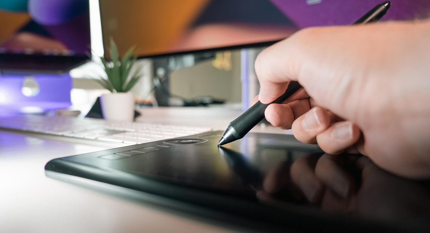 Detalle de una mano utilizando un lápiz óptico sobre una tableta digitalizadora para retoque fotográfico preciso.