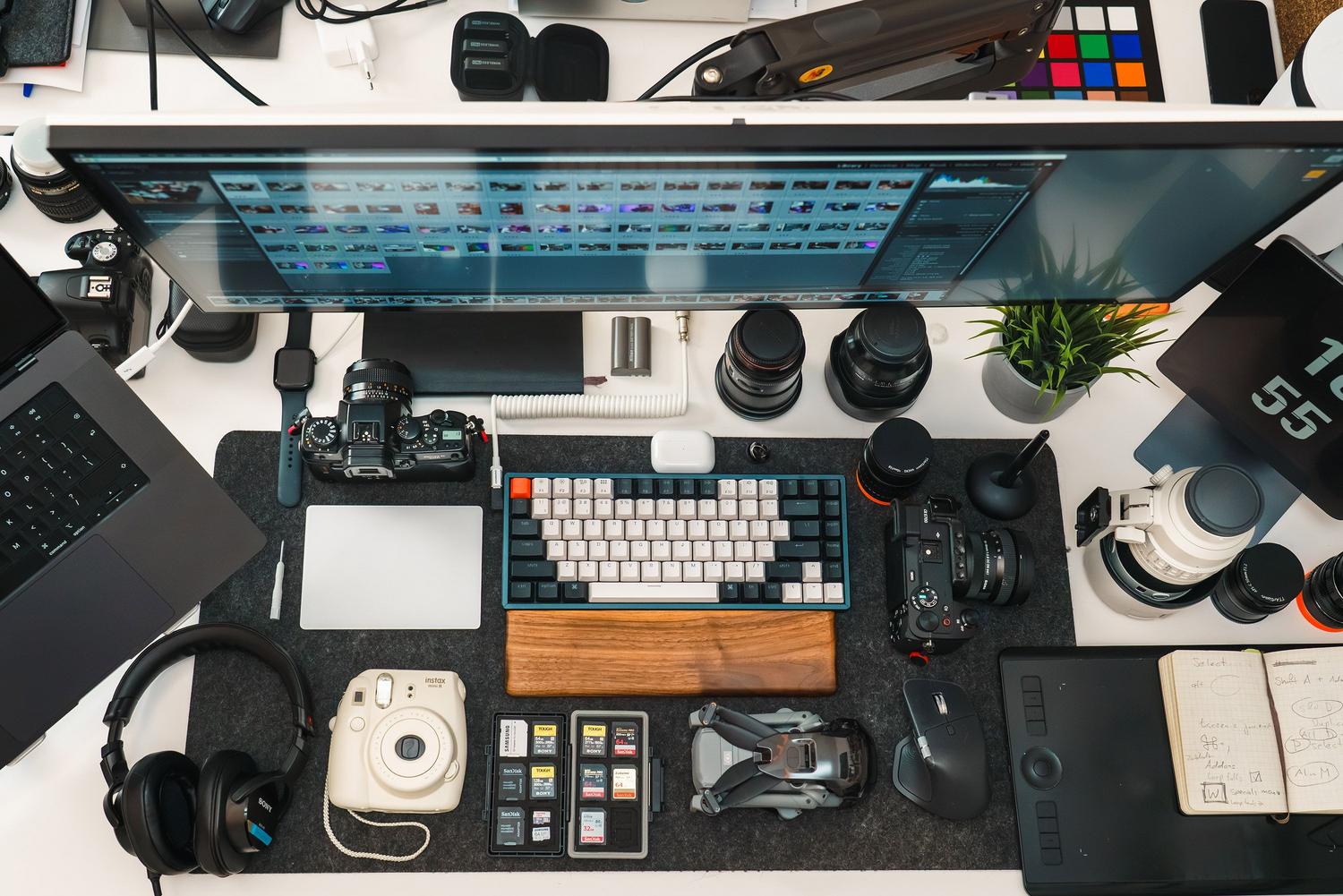 Vista cenital de un escritorio organizado con cámaras, lentes y periféricos de edición profesional.