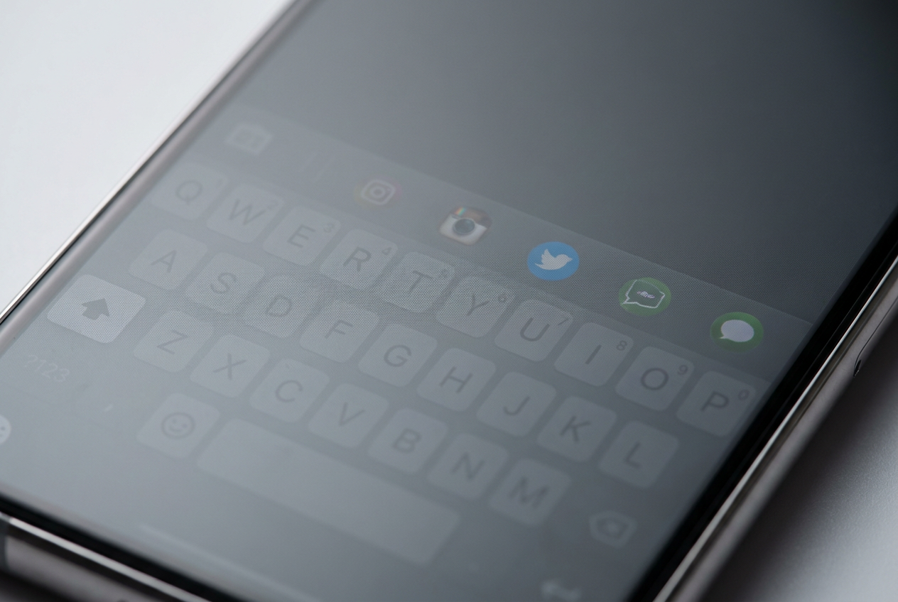 Primeiro plano de la pantalla de un smartphone con fondo gris donde se aprecian marcas fantasma de un teclado y iconos, ilustrando el efecto de burn-in.