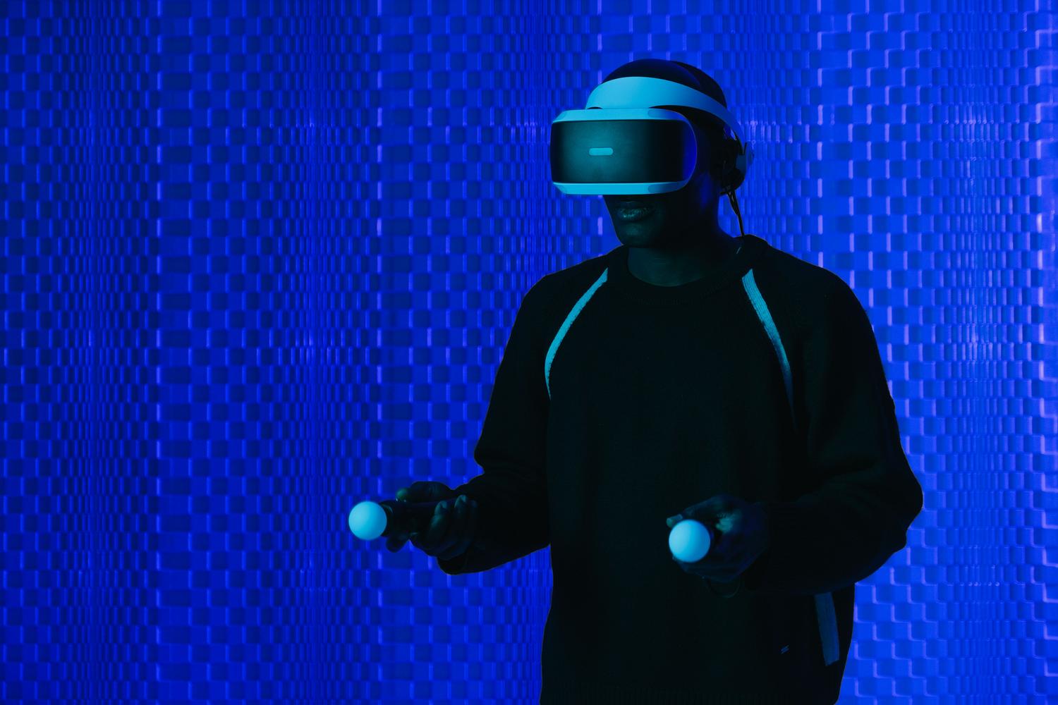 Hombre utilizando un casco de realidad virtual y mandos en un entorno futurista con iluminación azul neón, ilustrando el hardware necesario para la inmersión total.