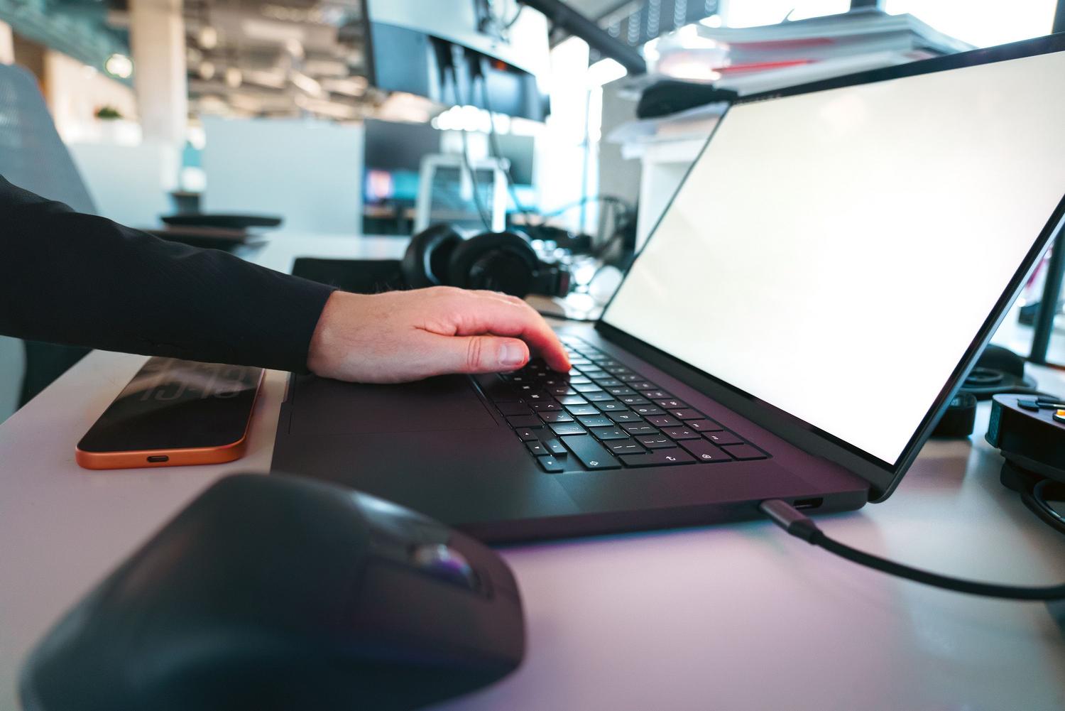 Persona escribiendo en un teclado de portátil en un entorno de oficina moderno, representando la búsqueda de soluciones técnicas.