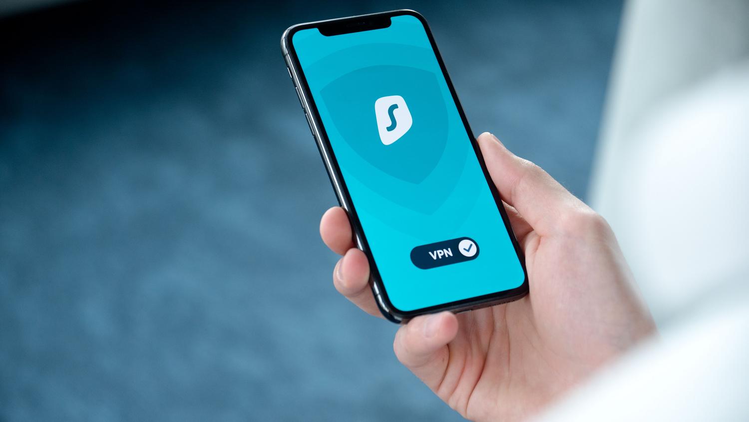 Mano sosteniendo un teléfono móvil con una aplicación de VPN activa, representando las medidas de protección avanzada recomendadas.