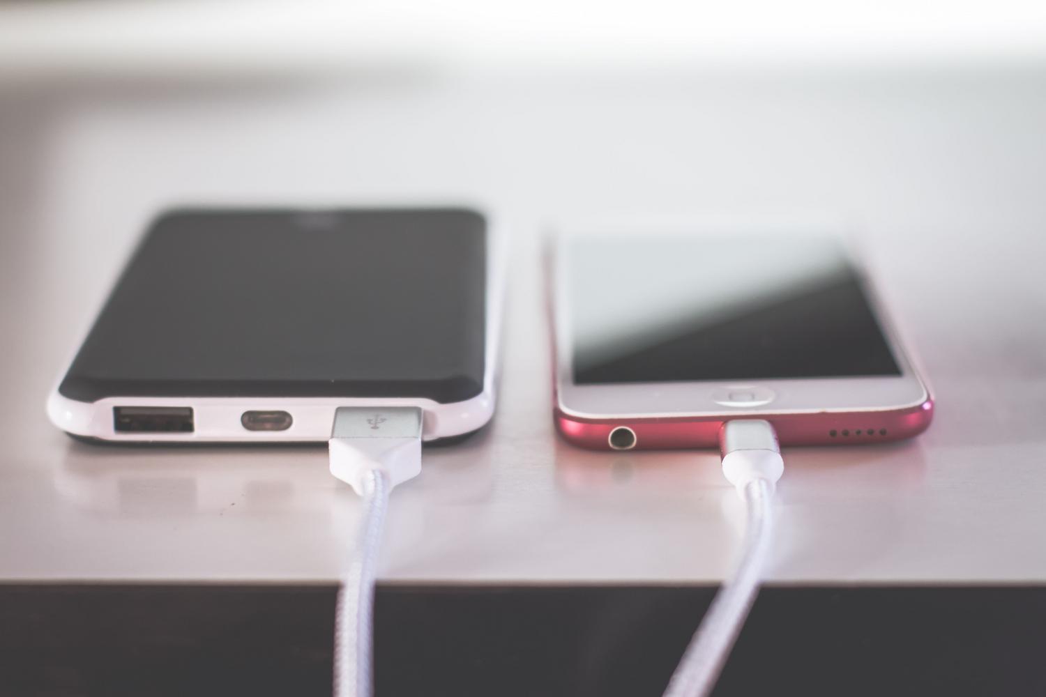 Dos smartphones modernos cargándose sobre una mesa, ejemplificando el proceso de recarga y la conversión de energía en calor.