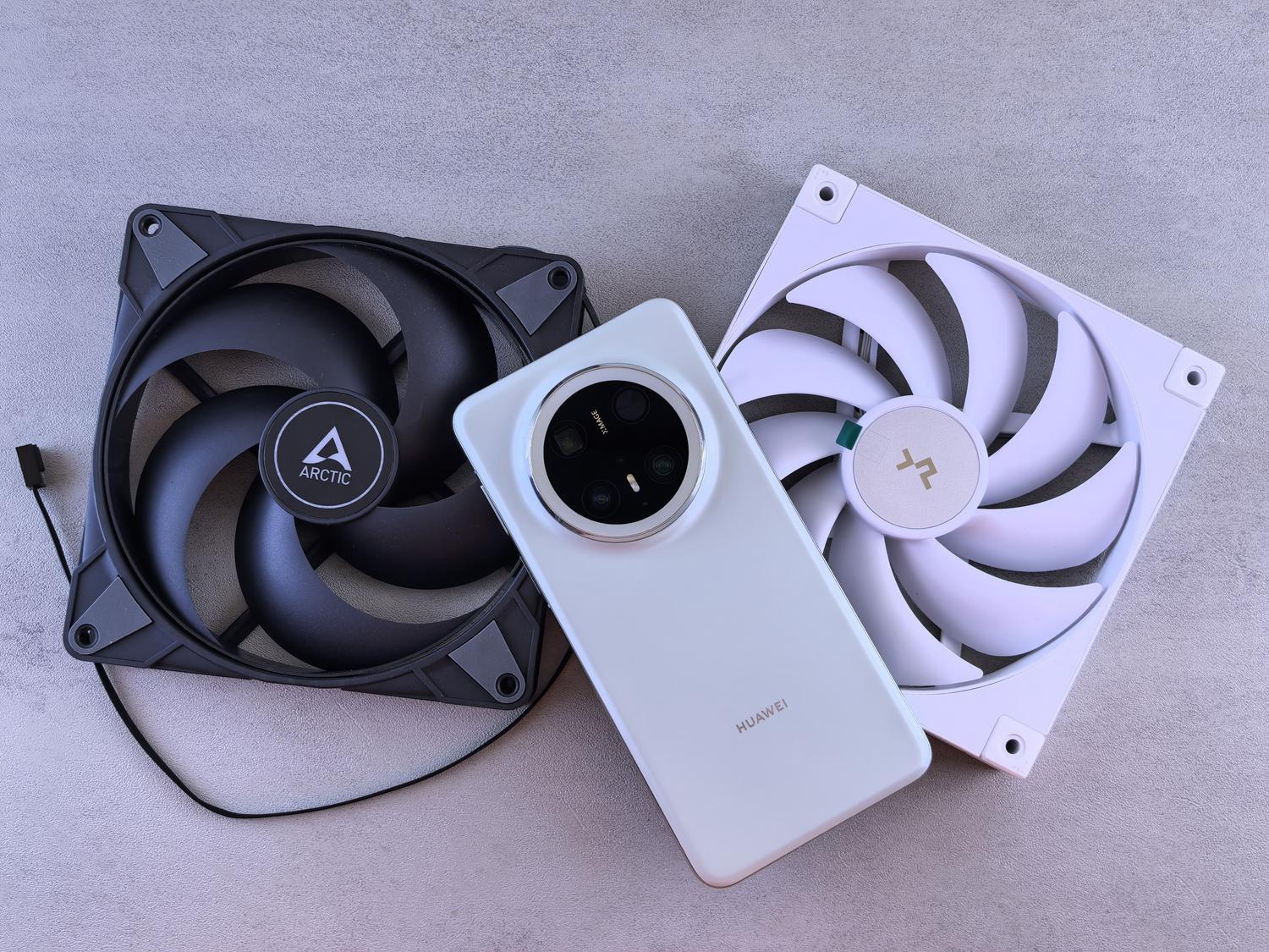 Smartphone junto a ventiladores de refrigeración sobre una superficie gris, mostrando la importancia de buscar ventilación para enfriar el dispositivo.