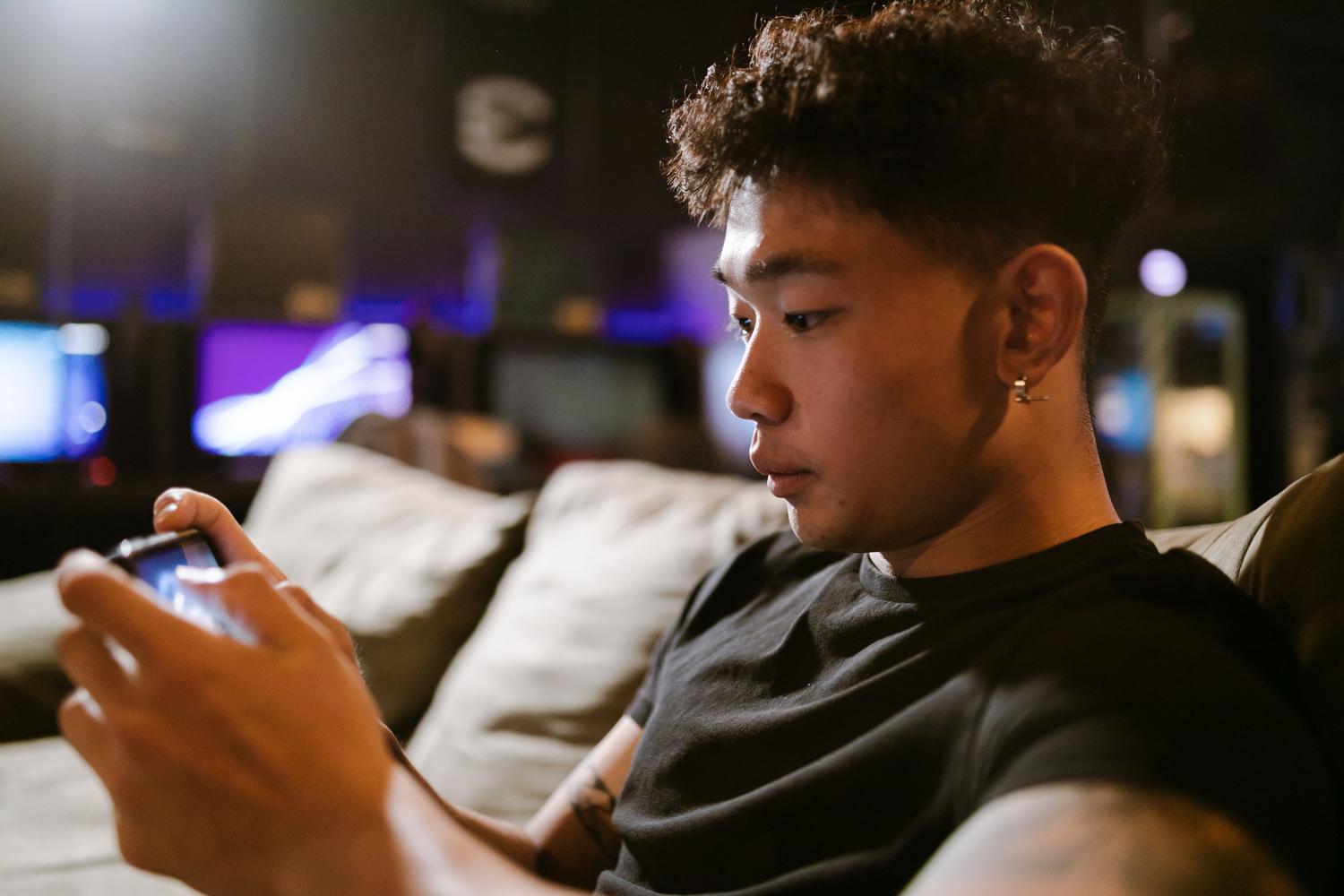 Hombre concentrado jugando un videojuego intensamente en su smartphone, ilustrando el uso intensivo de hardware que genera calor.