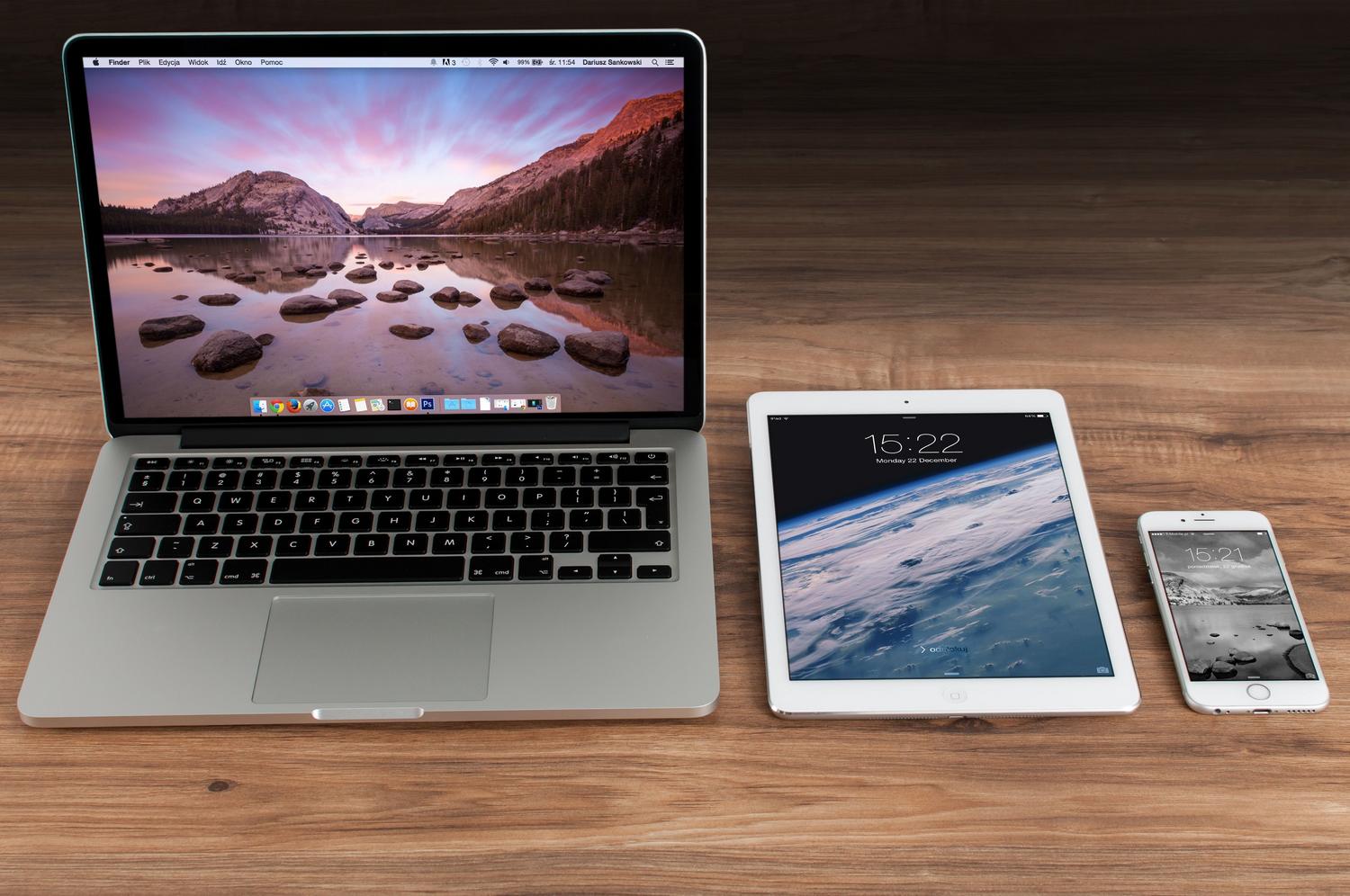 Espacio de trabajo moderno con ordenador portátil, tableta y smartphone para ilustrar la sincronización de datos entre dispositivos.