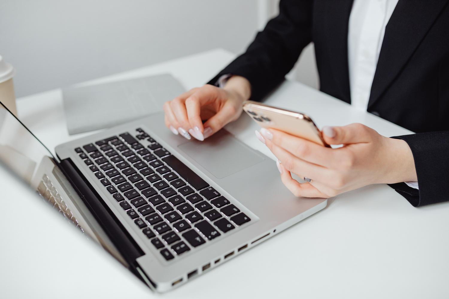 Profesional utilizando sus dispositivos en un entorno de oficina, ideal para representar la gestión de perfiles personales y profesionales.